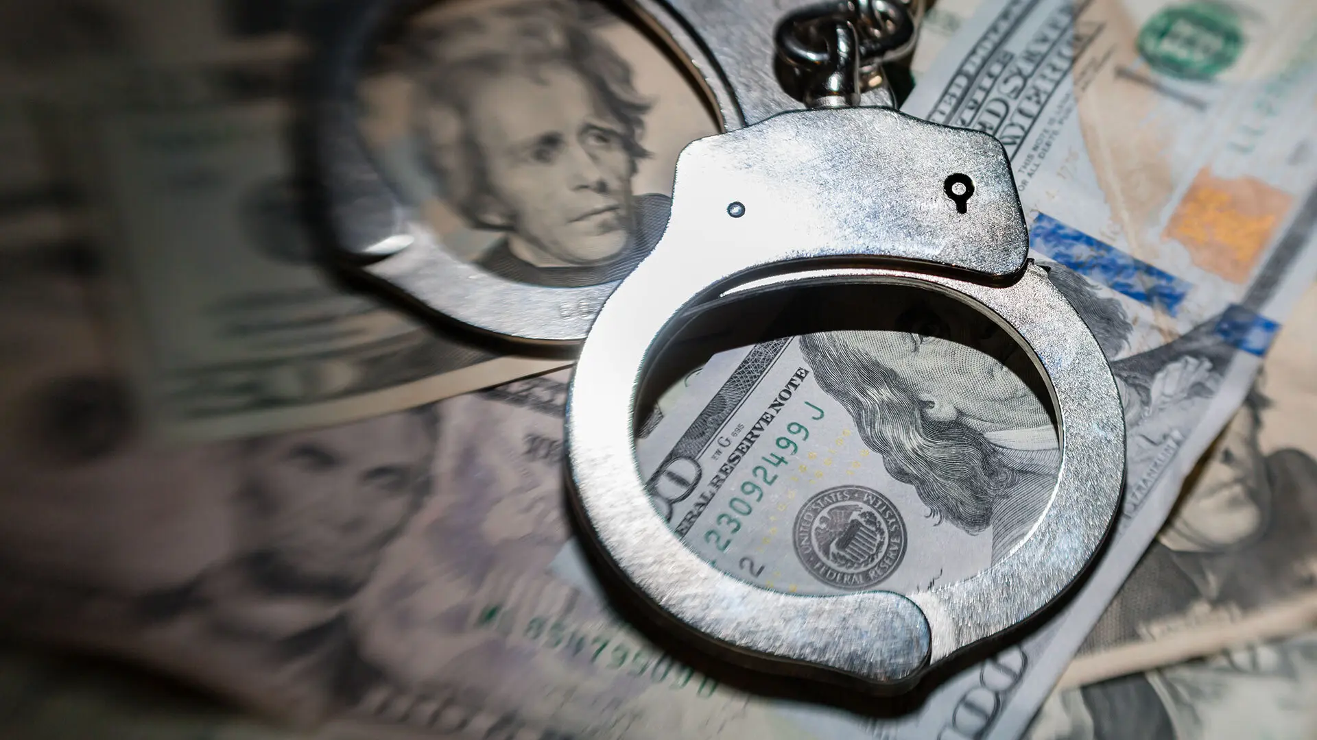 Image of currency notes with handcuffs on top of them.